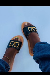 a pair of black sandals with a gold logo on them