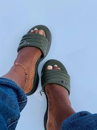 a woman's feet in a pair of green slide sandals