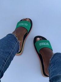 a woman's feet in a pair of green and black slide sandals